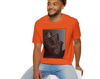 May include: A bright orange t-shirt with a black and white image of John Coltrane playing a saxophone. The image is framed in a black rectangle.