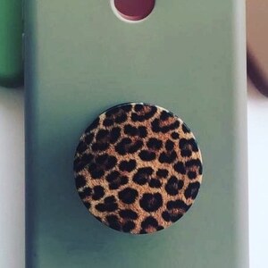 Pode incluir: Uma capa de telefone verde com um suporte de telefone de estampa de leopardo.