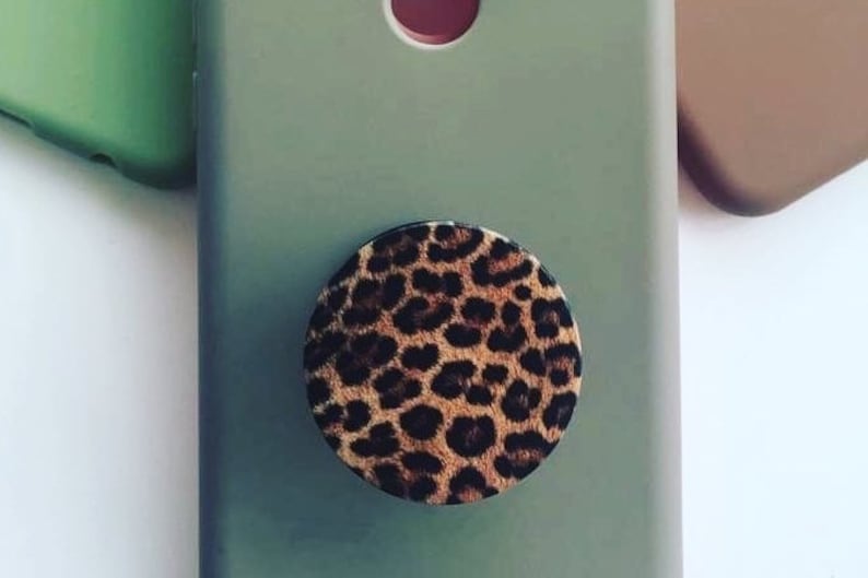 Pode incluir: Uma capa de telefone verde com um suporte de telefone de estampa de leopardo.