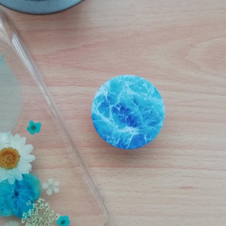 Pode incluir: Um suporte para telefone azul e branco com um padr&atilde;o de ondas.