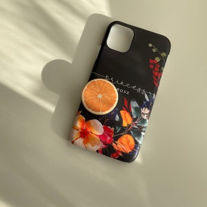 May include: Black phone case with a floral design featuring orange slices, red flowers, and green leaves. The text "princess rose" is printed on the case.