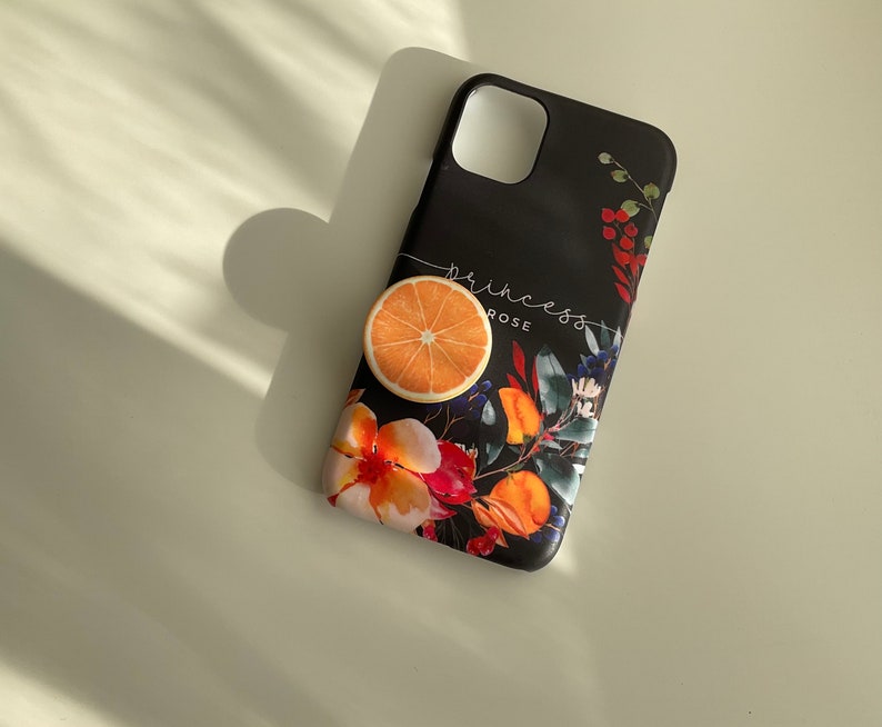 Pode incluir: Capa de telefone preta com um design floral que apresenta fatias de laranja, flores vermelhas e folhas verdes. O texto "princess rose" est&aacute; impresso na capa.