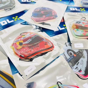 Puede incluir: Surtido de ambientadores para coche con varios dise&ntilde;os, incluyendo un casco de carreras rojo y blanco, un panda blanco y negro y un coche de carreras azul y blanco. Los ambientadores est&aacute;n envasados en bolsas de pl&aacute;stico transparentes con un logotipo azul y blanco que dice "DLX".