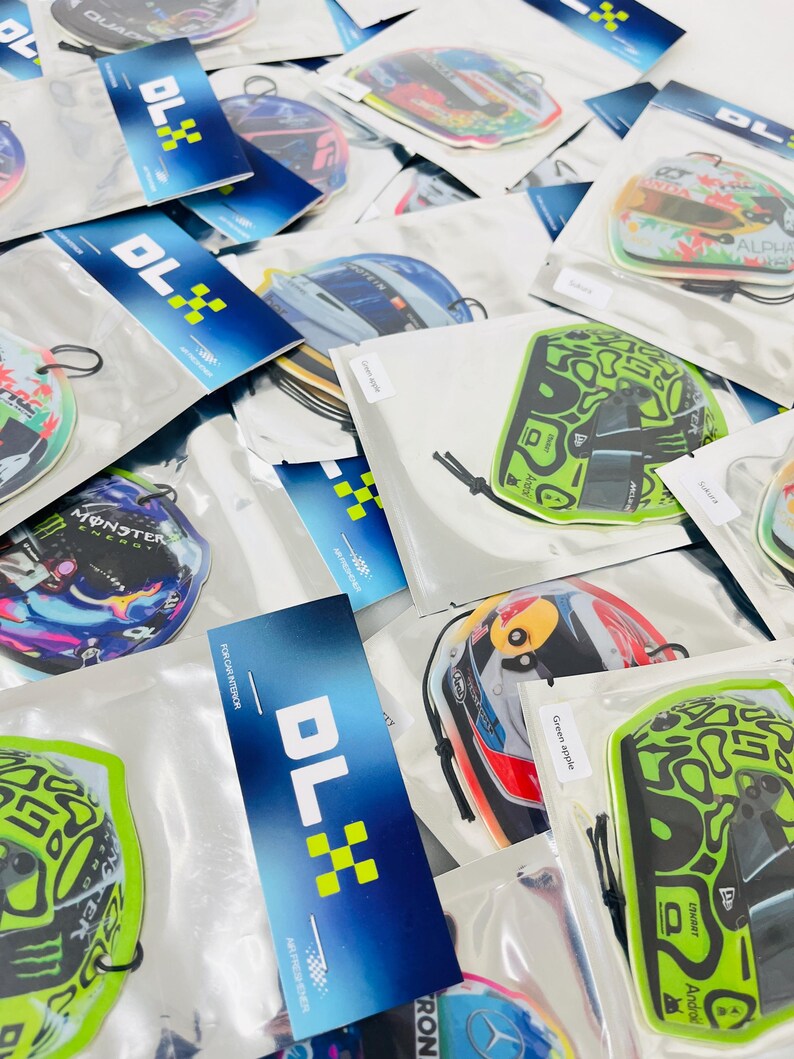 Puede incluir: Una variedad de ambientadores para coche con diferentes dise&ntilde;os, incluyendo un casco verde y negro, un casco rojo y blanco y un casco azul y blanco. Los ambientadores est&aacute;n empaquetados en bolsas de pl&aacute;stico transparentes con una etiqueta azul y blanca que dice "DLX".