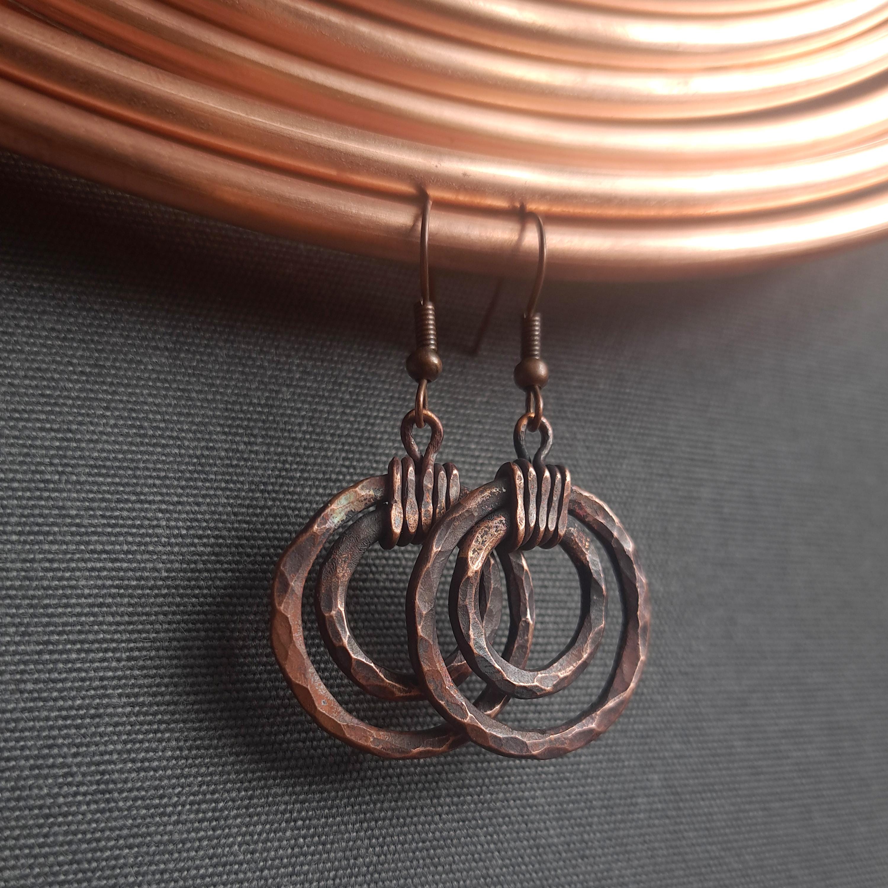 Handmade rustic copper earrings with hammered rings and coiled wire accents exuding unique artisanal charm.