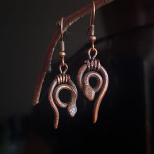 Pequeña serpiente de cobre para la oreja. Forjada a mano, con pátina natural, ultraligera.