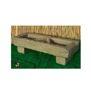 May include: A rustic stone trough planter with two compartments, featuring a weathered, aged look. The planter is raised on four short legs and is ideal for adding a touch of natural charm to any garden or outdoor space.