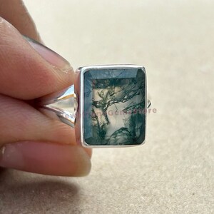 May include: A silver ring with a green moss agate gemstone. The gemstone has a unique, natural pattern of green and white.