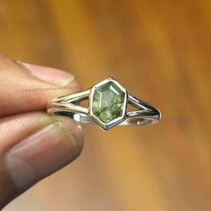 May include: A silver ring featuring a green moss agate gemstone. The ring has a split shank design.