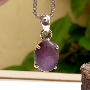 May include: A silver chain necklace with a purple oval gemstone pendant.