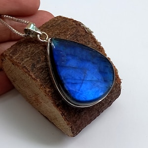 May include: A teardrop-shaped pendant with a blue labradorite gemstone set in silver. The pendant is hanging from a silver chain.