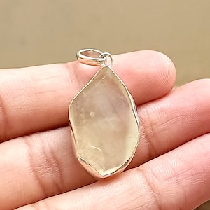 May include: A clear, faceted, teardrop-shaped gemstone pendant with a silver bail.