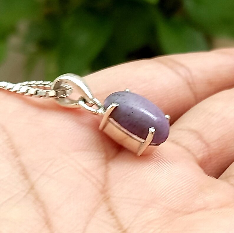 May include: A silver pendant necklace with a purple gemstone. The pendant is oval shaped and has a silver setting.