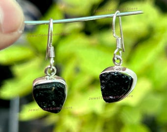 May include: A pair of silver earrings with black gemstone drops. The earrings have a simple design and are perfect for everyday wear.
