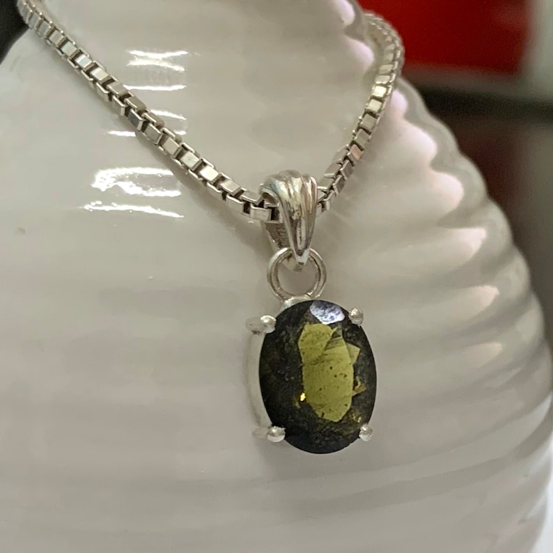 Op de afbeelding: Een zilveren ketting met een hanger met een donkergroene ovale edelsteen.