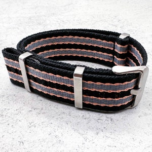 May include: A black and grey striped watch strap with silver hardware. The strap is made of nylon and has a woven design.
