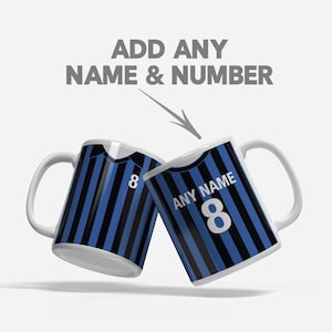 Könnte beinhalten: Zwei weiße Keramikbecher mit einem Fußballtrikot-Design. Die Becher sind schwarz-blau gestreift mit der weißen Nummer 8. Über den Bechern steht "ADD ANY NAME & NUMBER" mit einem Pfeil, der auf die Becher zeigt.