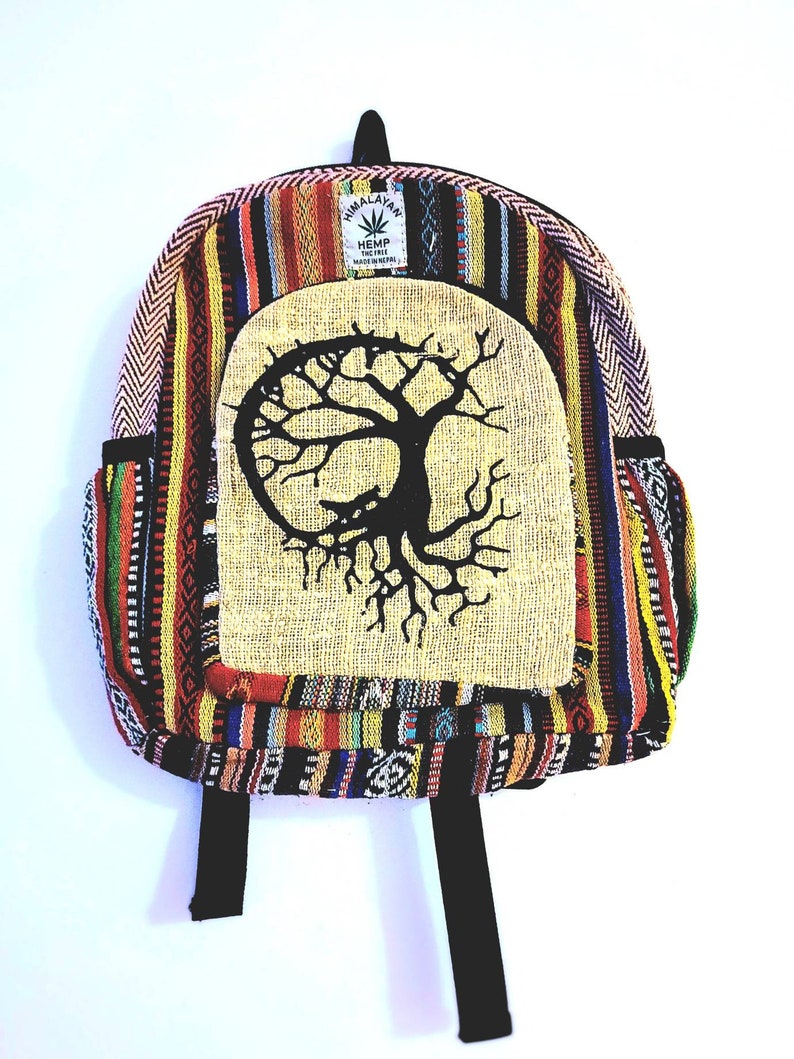 Puede incluir: Mochila colorida con dise&ntilde;o de &aacute;rbol de la vida. La mochila presenta un panel central con un gr&aacute;fico de &aacute;rbol negro sobre un fondo beige. Est&aacute; hecha de tela tejida con una variedad de colores y patrones, incluyendo rojo, amarillo y azul.