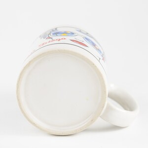 May include: White ceramic mug with a blue and red cartoon design and the text "San Diego" on the side.