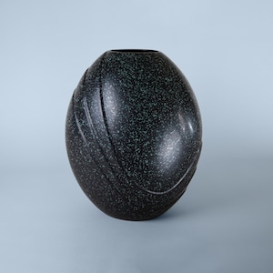May include: A black and green speckled ceramic vase with a rounded, egg-shaped design.