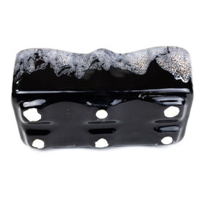 May include: Black ceramic planter with a white glaze pattern. The planter has four drainage holes on the bottom.