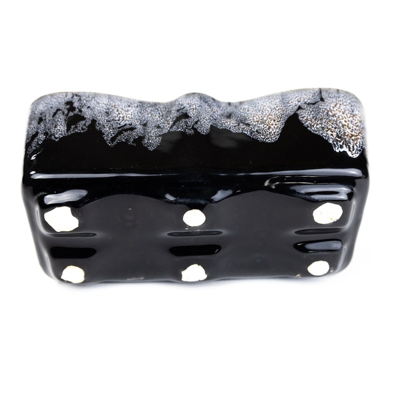 May include: Black ceramic planter with a white glaze pattern. The planter has four drainage holes on the bottom.