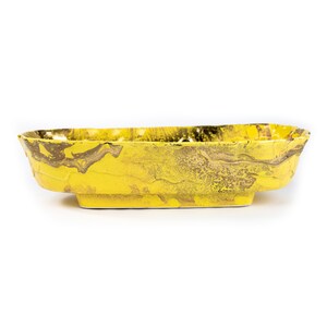 May include: A yellow ceramic serving bowl with a marbled design. The bowl has a slightly rounded rectangular shape and a raised lip around the edge.