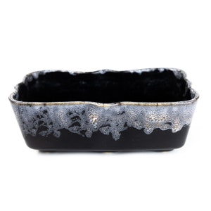 May include: A black ceramic rectangular planter with a white and gold speckled glaze.