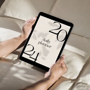 May include: A black tablet with a white screen displaying a daily planner with the text "daily planner" and the numbers "20" and "24" on the screen.