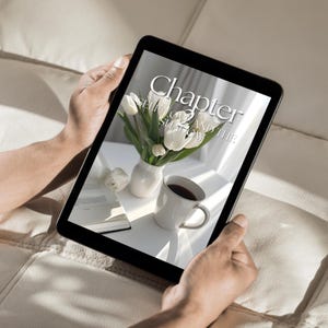 May include: A person is reading a digital book on a tablet. The book cover features the text "Chapter 2 Self Love and the Shadow". The cover also features a bouquet of white tulips in a white vase and a cup of coffee.