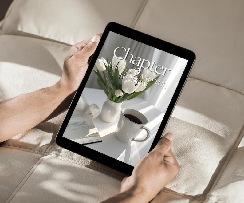 May include: A person is reading a digital book on a tablet. The book cover features the text "Chapter 2 Self Love and the Shadow". The cover also features a bouquet of white tulips in a white vase and a cup of coffee.