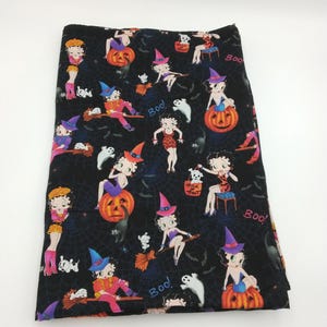May include: Black fabric with a Halloween-themed pattern featuring Betty Boop characters in witch costumes, pumpkins, ghosts, and the word "Boo!". The design includes spiderwebs and a "Trick or Treat" sign.