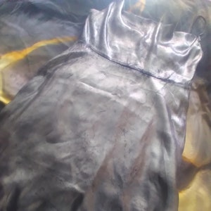 May include: A black satin slip dress with a simple design. The dress is made of a soft, flowing fabric and has a relaxed fit.
