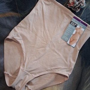 May include: A pair of beige high-waisted briefs with extra firm control. The garment features a smooth, solid-colored fabric and includes a product tag labeled Underscore Extra Firm Control, Sheer Hi-Waist Brief, and size XXL, showing a model illustration.