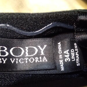 May include: Black strapless bra with the text "BODY BY VICTORIA" on a tag. The tag also indicates a 34A size and "MADE IN CHINA". The bra is lined.
