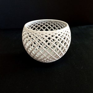 May include: White ceramic bowl with a geometric lattice design. The bowl is round and has a wide opening.