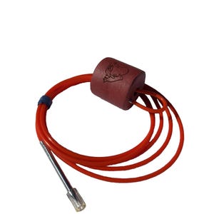 May include: A cylindrical red foam float attached to a long, coiled orange cord. The float features a small black line drawing of a fish. A metallic silver-toned connector with a clear plastic tip is attached to the end of the orange cord.