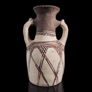 May include: A small, white ceramic vase with two handles and a geometric design in brown and red. The vase has a narrow neck and a rounded body.