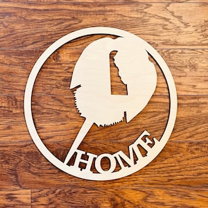May include: A wooden circle with a cutout of a horseshoe crab and the word "HOME" written underneath. The circle is on a woodgrain background.