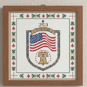May include: Cross-stitch artwork in a wooden frame. The design features the American flag within a shield, the Liberty Bell, and the text "250 1776-2026". The border includes red, green, and gold decorative elements.