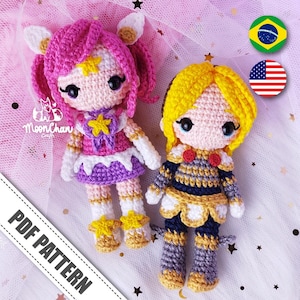May include: Two handmade crochet dolls. One doll has pink hair, a star-shaped accessory, and a purple and white dress. The other doll has yellow hair and a blue, gold, and white outfit. The text "PDF PATTERN" is visible.