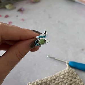 May include: A silver ring with a green stone and turquoise accents. The ring is shaped like a peacock with its head and tail feathers.