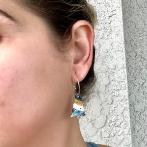 May include: Abalone shell earrings with a tree design. The earrings have a silver hook and a colorful, layered design with blue, white, yellow, and red accents. The earrings are a unique and eye-catching accessory.
