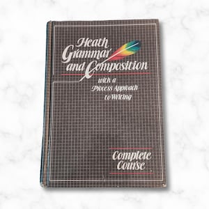 May include: A vintage textbook titled "Heath Grammar and Composition" with a process approach to writing. The book is brown with a grid pattern and the title is in white and red lettering. The book also says "Complete Course" in red lettering.