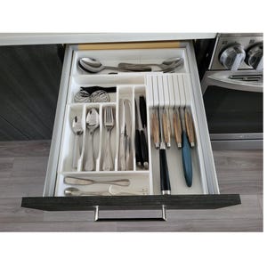 May include: An open kitchen drawer with a white cutlery organizer. The drawer contains various silverware, including spoons, forks, knives, and serving utensils. The silverware is arranged neatly in the compartments.