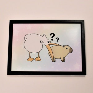 Op de afbeelding: Een ingelijste illustratie van een witte vogel met een lange oranje snavel die naar een bruin capybara kijkt met de vraagtekens "??" boven de kop van de vogel.