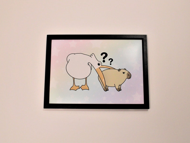 Op de afbeelding: Een ingelijste illustratie van een witte vogel met een lange oranje snavel die naar een bruin capybara kijkt met de vraagtekens "??" boven de kop van de vogel.