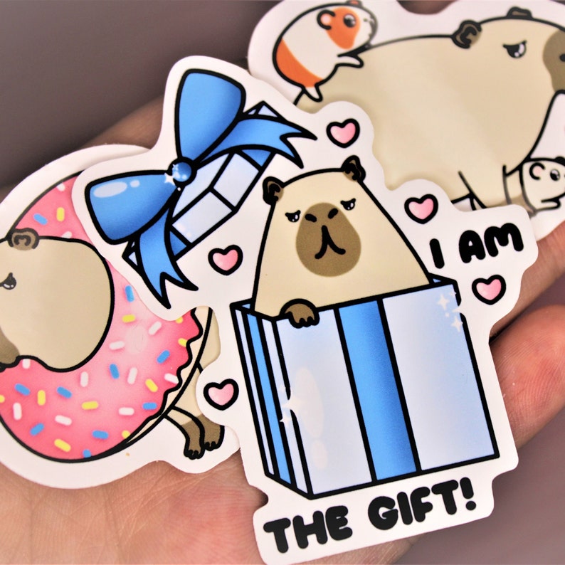 Op de afbeelding: Een set van vier stickers met een mopshond in verschillende poses. E&eacute;n sticker toont de mopshond met een roze donut, een andere toont de mopshond in een blauwe cadeaudoos met een blauwe strik, en de andere twee stickers tonen de mopshond met de tekst "Ik ben het cadeau!" en een hartje.