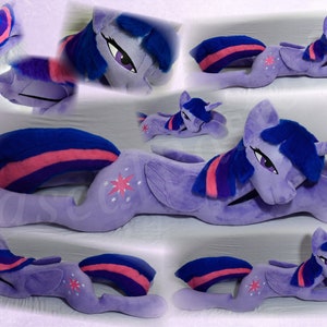 Könnte beinhalten: Ein großes lilafarbenes Plüschtier von Twilight Sparkle aus My Little Pony. Das Spielzeug liegt auf der Seite, der Kopf ruht auf dem Vorderbein. Das Spielzeug hat eine blaue Mähne und einen blauen Schwanz mit rosa Streifen, ein lilafarbenes Horn und einen rosa-weißen Stern auf der Flanke.