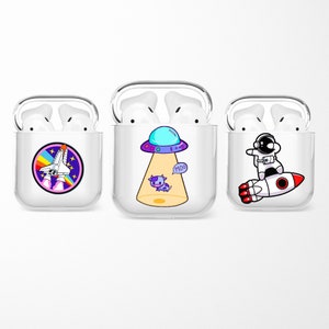 Puede incluir: Tres estuches de plástico transparente para Airpods con diferentes diseños de dibujos animados coloridos. El primer estuche tiene un cohete con un arcoíris y estrellas. El segundo estuche tiene una nave espacial extraterrestre morada con una vaca que dice "Moo". El tercer estuche tiene un astronauta montando un cohete.